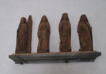 Over døren til sakristiet står på en hylde fire nødhjælperhelgeninde-figurer af træ